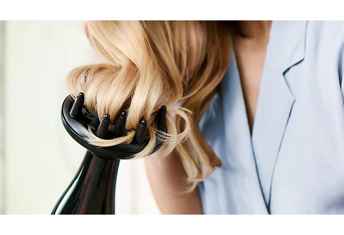 Μια γυναίκα στεγνώνει τα μαλλιά της με τη φυσούνα.